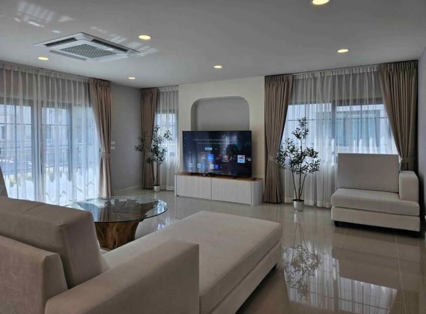 Detached House for rent in Bang Phli, Samut Prakan - Spacious lounge with multiple windows, modern media wall, soft seating and glossy tiled flooring.