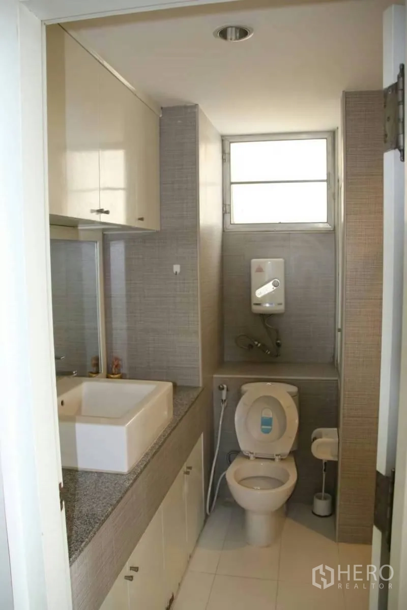 Condominium for rent in Watthana, Bangkok - Second bathroom with countertop basin, storage cabinets, toilet and window.
