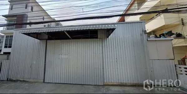 Warehouse for rent in Bang Kapi, Bangkok - Corrugated metal warehouse exterior with a wide sliding gate and canopy in Bang Kapi, Bangkok.