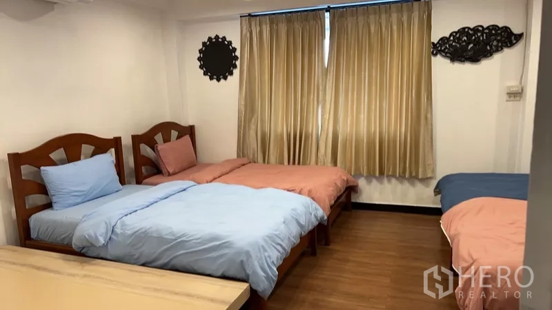 带办公室的家 出租或出售在Phra Khanong, Bangkok - 卧室配多张单人床，米色窗帘与木纹地板。