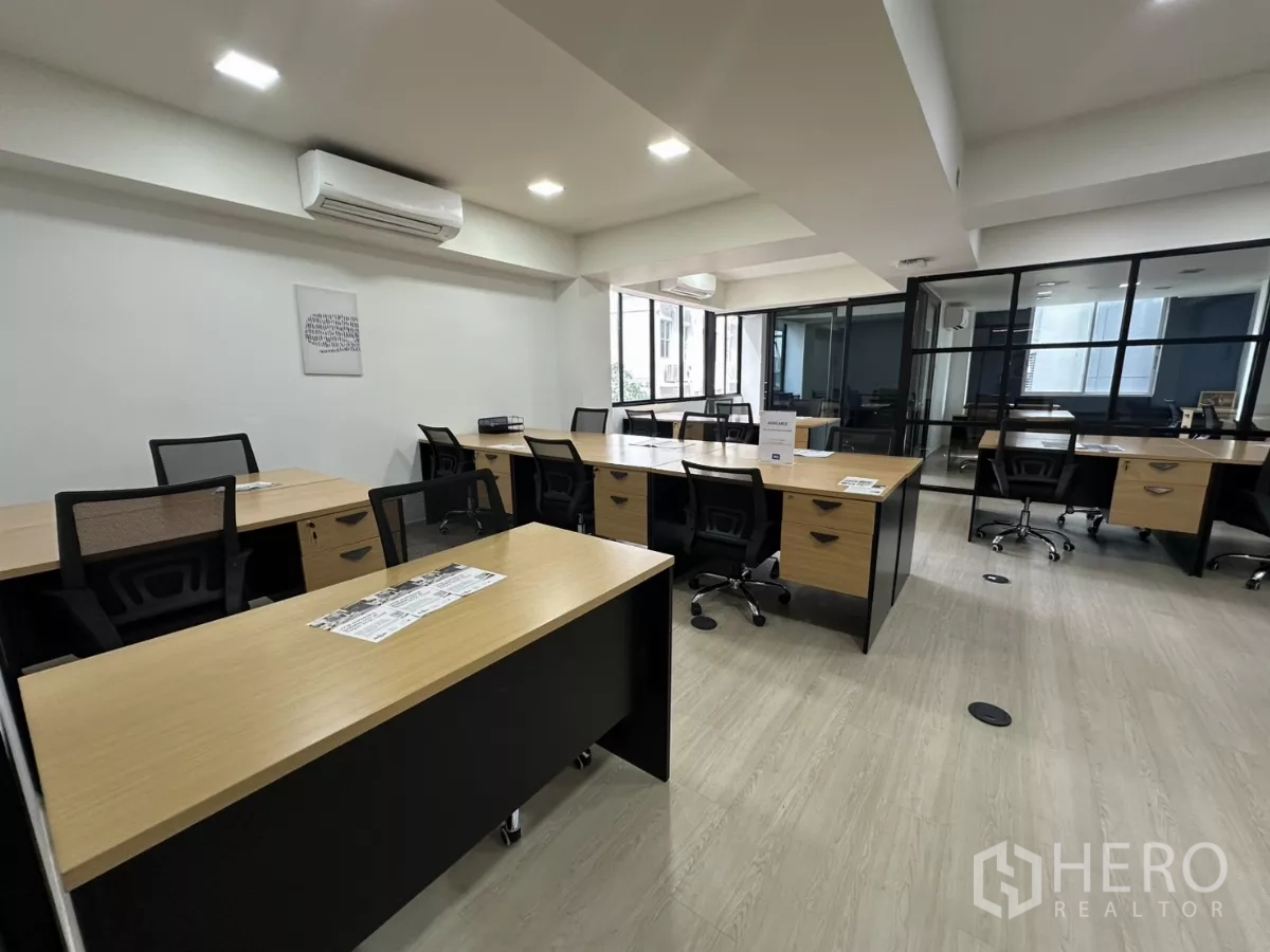 Office Space for rent in Watthana, Bangkok - Open-plan office with wood desks, mesh chairs, LED lighting and a glass-partitioned meeting room.