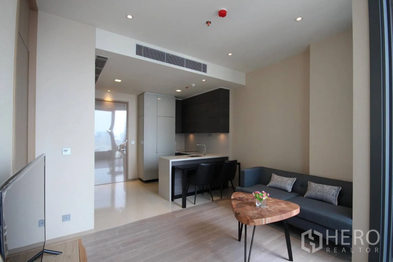 Condominium for rent in Watthana, Bangkok - Open-plan living area with modern kitchenette, island dining and recessed lighting.