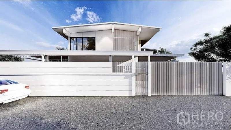 独立式住宅 出租在Lat Phrao, Bangkok - 现代两层独栋住宅，白色外立面，高隐私围墙与铺装车道，蓝天下位于拉抛。