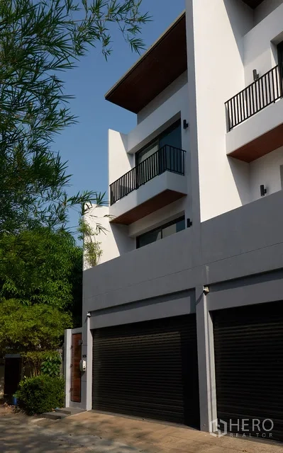 联排别墅 出租在Watthana, Bangkok - 当代外观侧视图，带阳台与双车库。