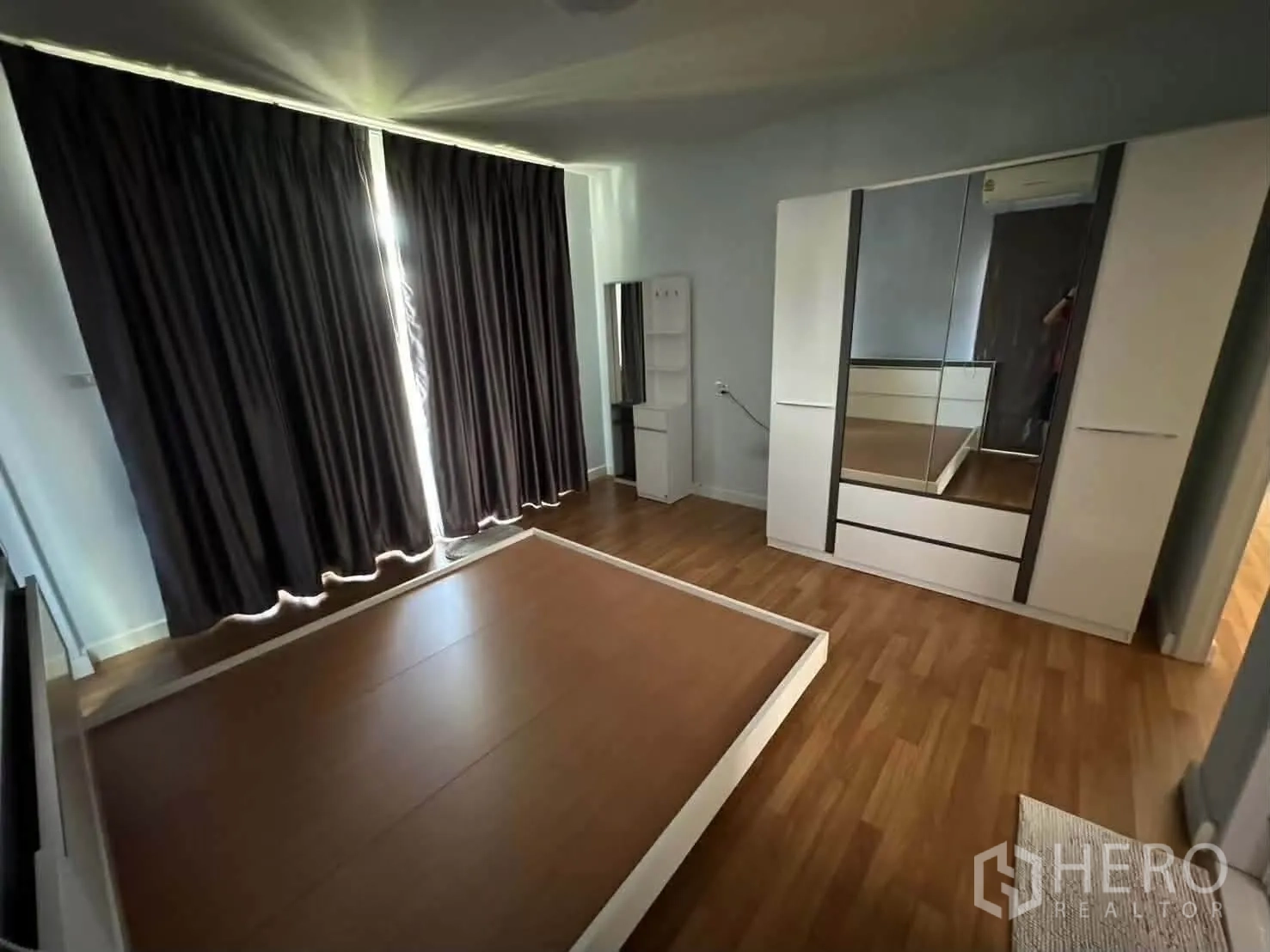 Detached House for rent in Watthana, Bangkok - Bedroom with wood flooring, bed base, mirrored wardrobe, and blackout curtains.
