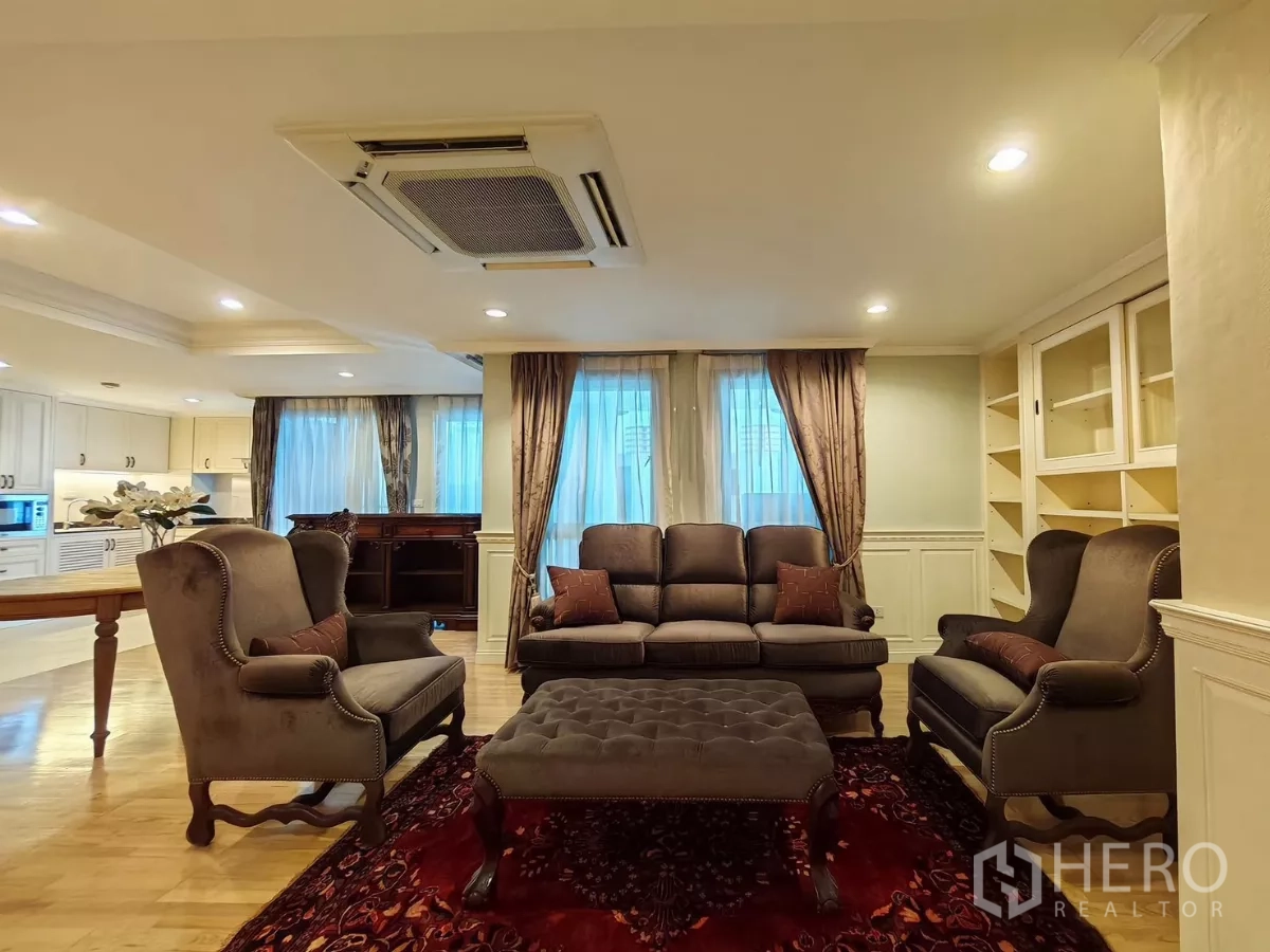 คอนโด ให้เช่าในPathum Wan, Bangkok - มุมนั่งเล่นโทนคลาสสิก โซฟาเซ็ตพร้อมสตูลบนพรมแดง รายล้อมด้วยผ้าม่าน