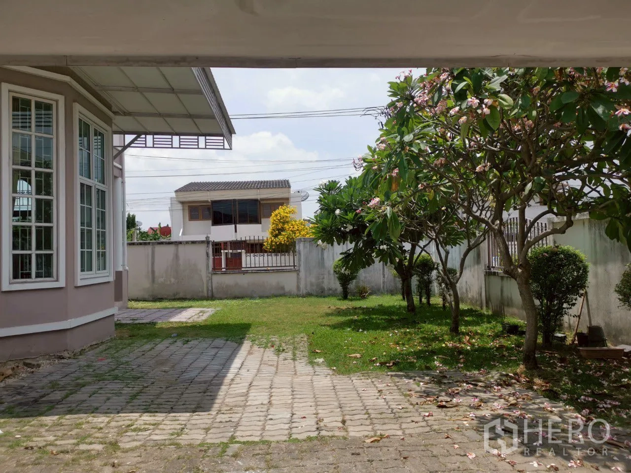 บ้าน ขายในPhra Khanong, Bangkok - มุมสนามหน้าบ้านจากโรงจอดรถ เห็นหน้าต่างบานเบย์ ลานจอด และต้นไม้ดอก