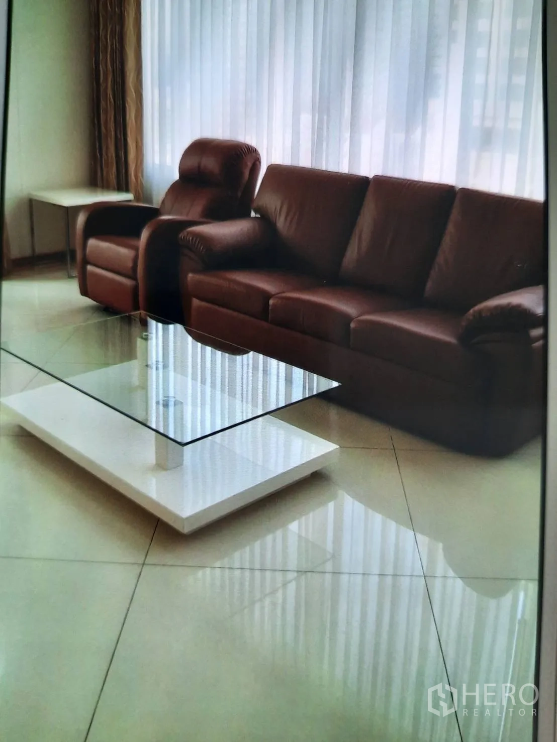 คอนโด ให้เช่าหรือขายในSathon, Bangkok - โซฟาหนังพร้อมโต๊ะกลางกระจกในมุมนั่งเล่นรับแสงกับผ้าม่านโปร่ง