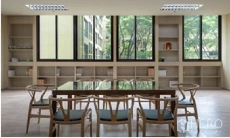 办公空间 出租在Chatuchak, Bangkok - 现代会议区，玻璃桌与木椅，内置书架，大窗外景观绿意盎然。