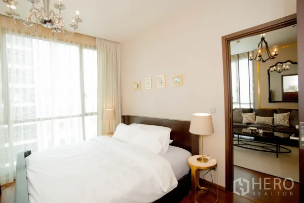 Condominium for rent in Watthana, Bangkok - Sunlit bedroom with floor-to-ceiling windows, double bed, sheer curtains, and a view into the living room.