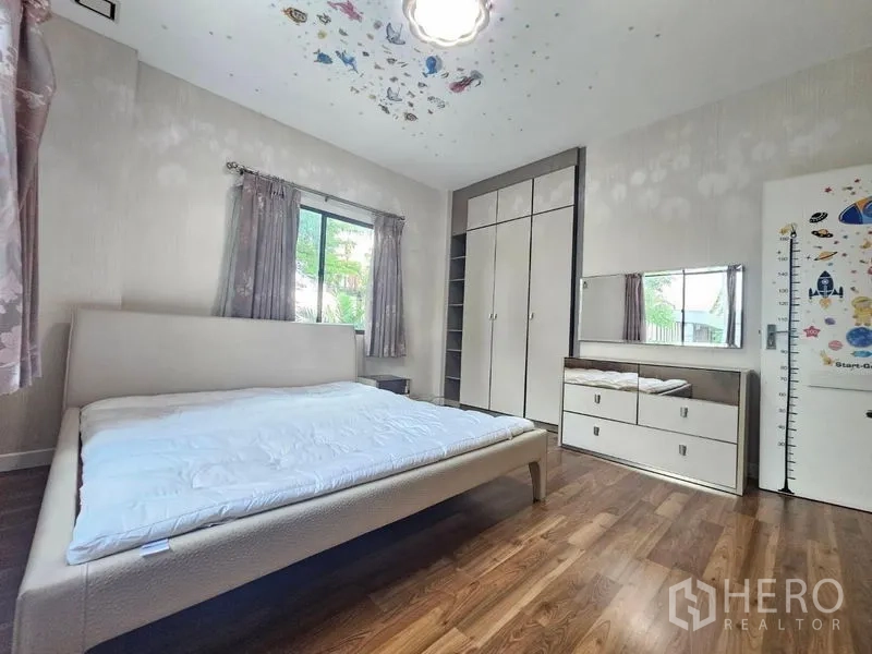Detached House for sale in Prawet, Bangkok - Bright second bedroom with built‑in wardrobe, dresser, wood floor and window.