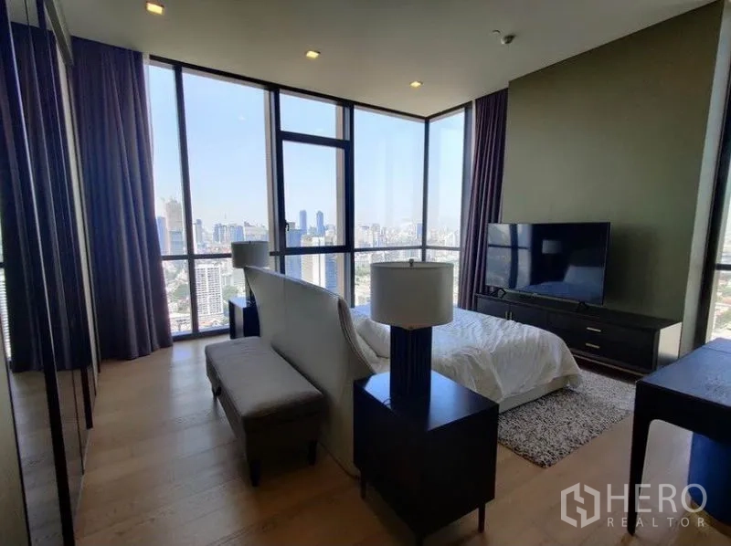 Condominium for rent in Watthana, Bangkok - Spacious master suite with TV console, bench seating, and corner windows revealing skyline vistas.