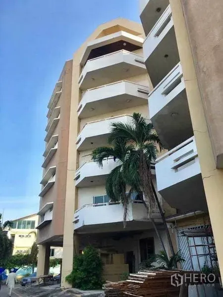 零售空间 出售在Phra Khanong, Bangkok - 帕卡农零售大楼，层层阳台外立面，前方有棕榈树。