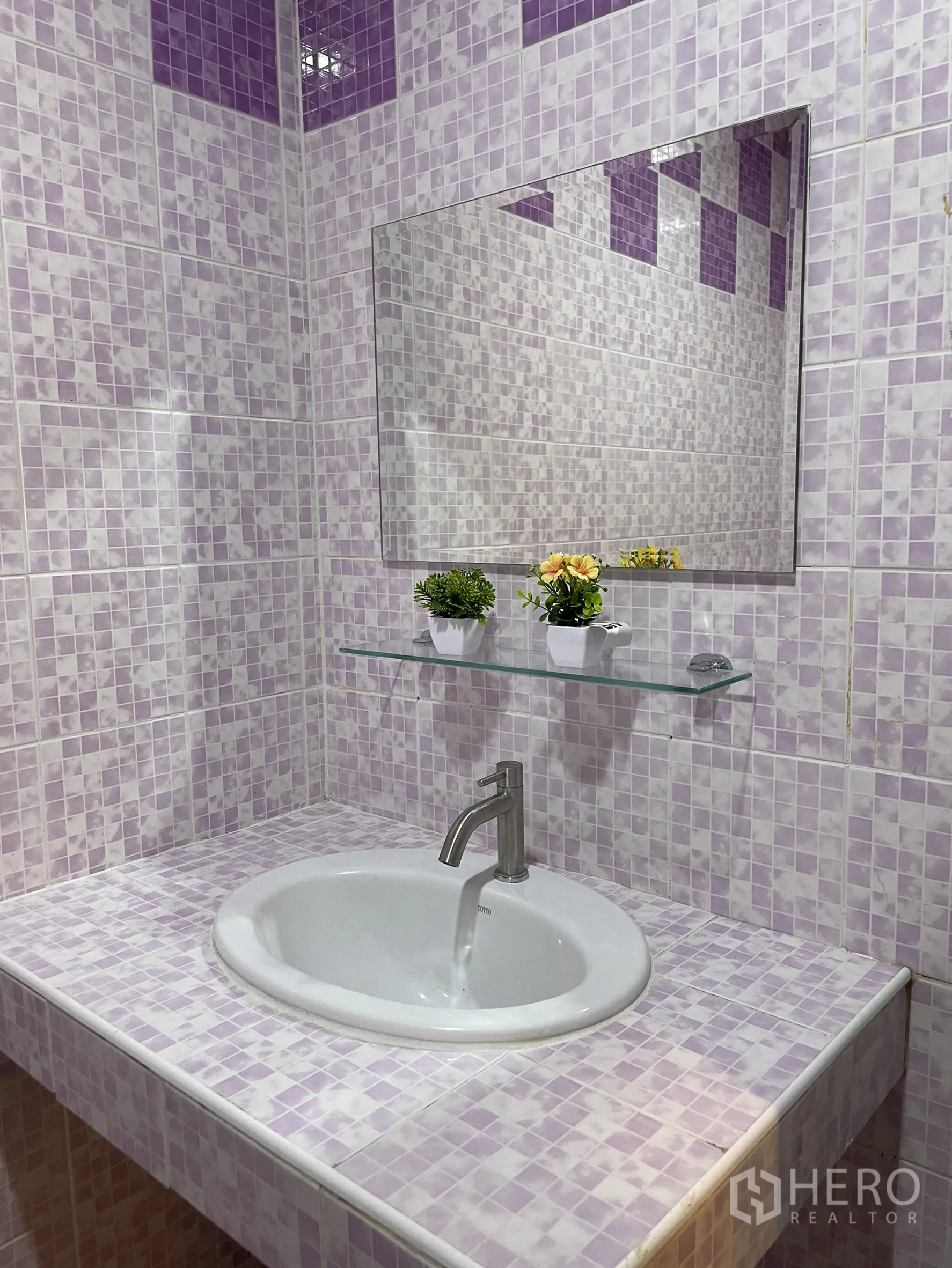 Shophouse for rent in Bang Kapi, Bangkok - Bathroom vanity with purple mosaic tiles, oval sink, mirror and small decorative plants.