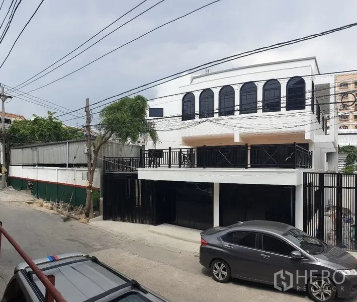带办公室的家 出租或出售在Bang Na, Bangkok - 街景视角，带大露台与黑色围栏的建筑。