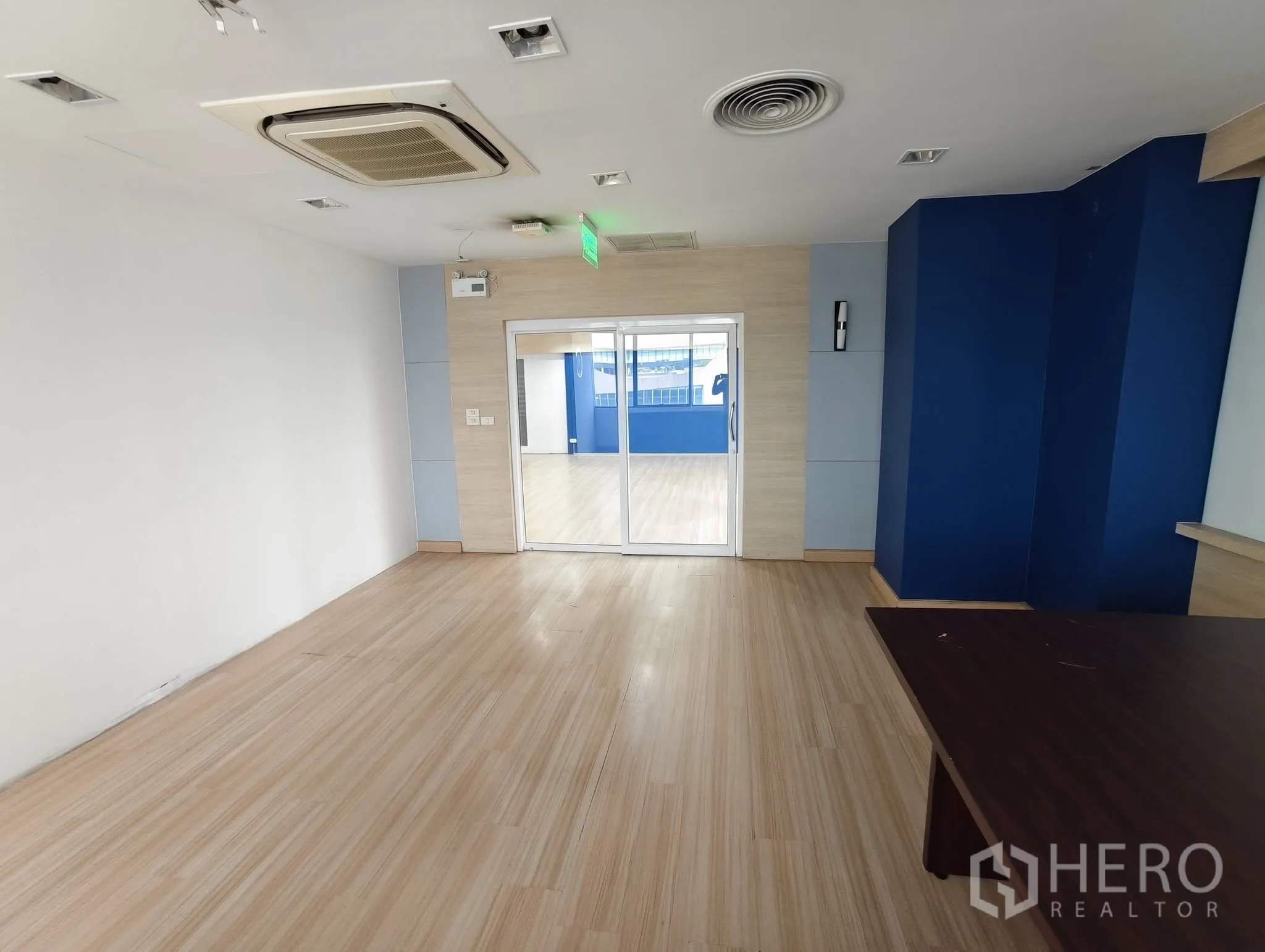 Office Space for rent in Lak Si, Bangkok - Open office with light wood flooring, blue accent wall, and sliding glass doors.