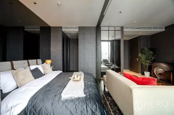 公寓 出租或出售在Khlong Toei, Bangkok - 特大床、沙发、深色大理石地面与镜面衣柜门。