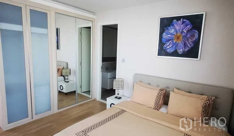 Condominium for rent in Watthana, Bangkok - Bedroom showing mirrored wardrobe and doorway to a modern bathroom.