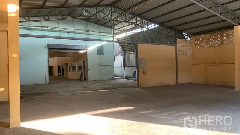 Warehouse for rent in Mueang Nakhon Pathom, Nakhon Pathom - Spacious covered bay beneath a steel roof with ventilation block wall and electrical panel.