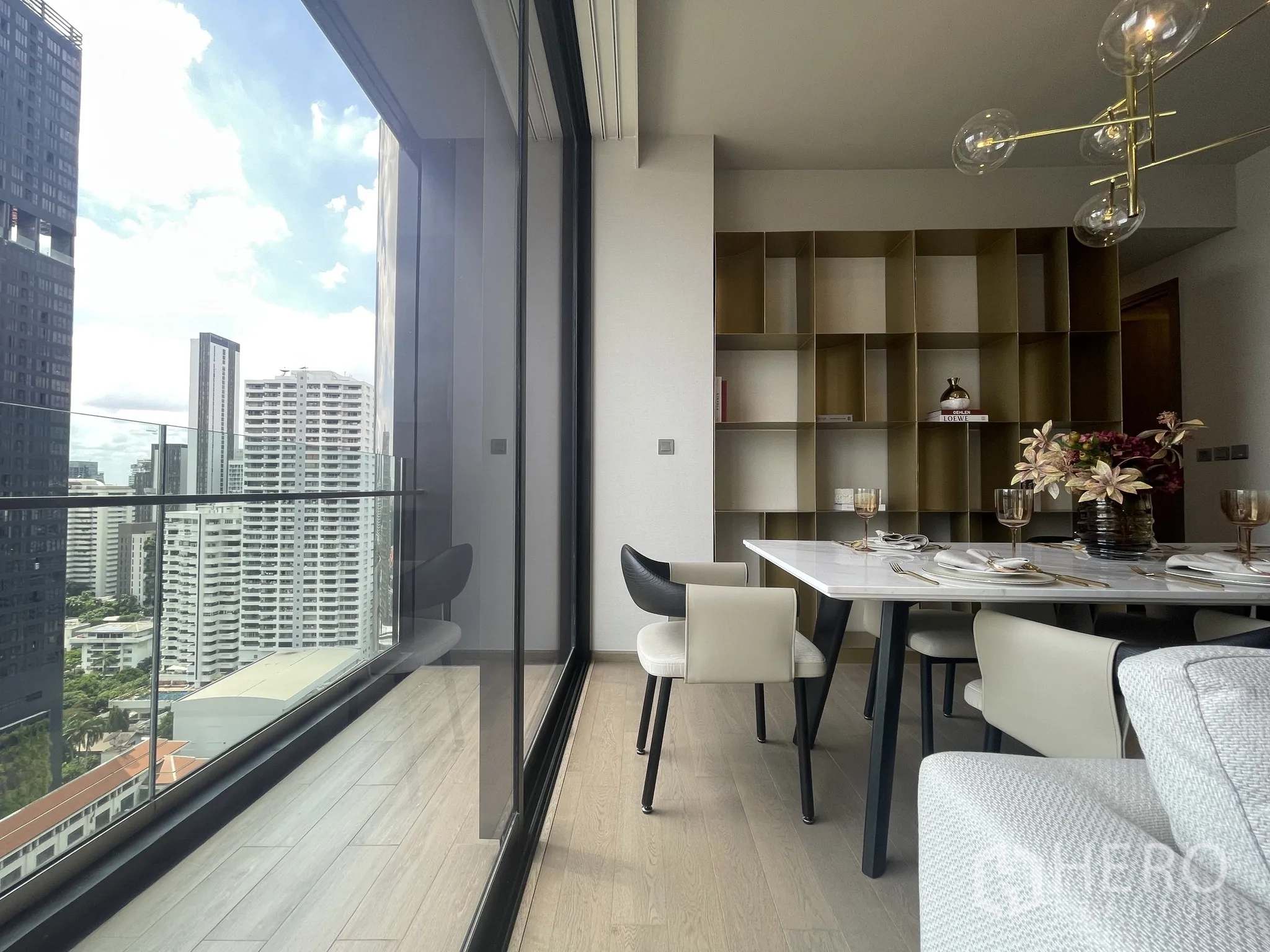 Condominium for rent in Watthana, Bangkok - Dining area beside large glass windows opening to a balcony with skyline views.