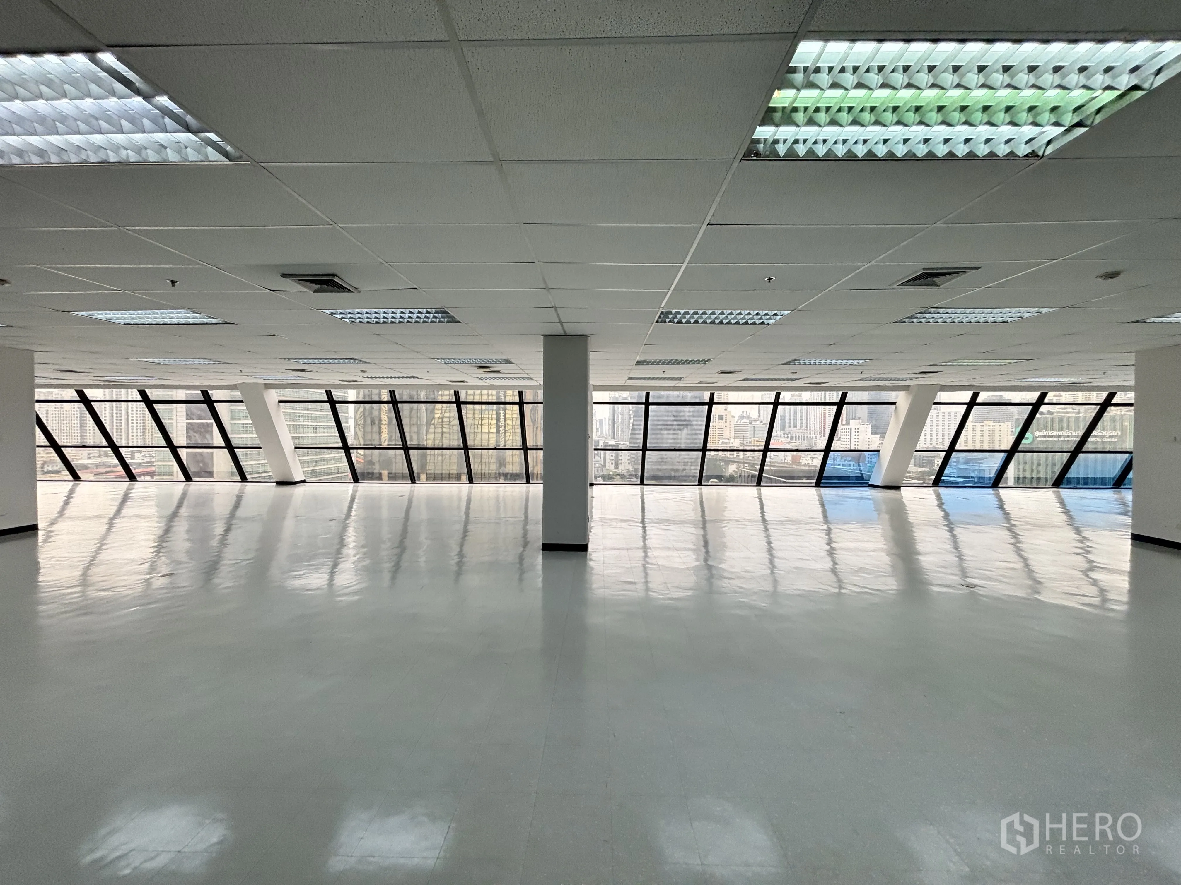 办公室 for rent in Ratchathewi, Bangkok - 宽敞办公区域，连续玻璃窗面朝城市景观，网格吊顶配荧光灯。