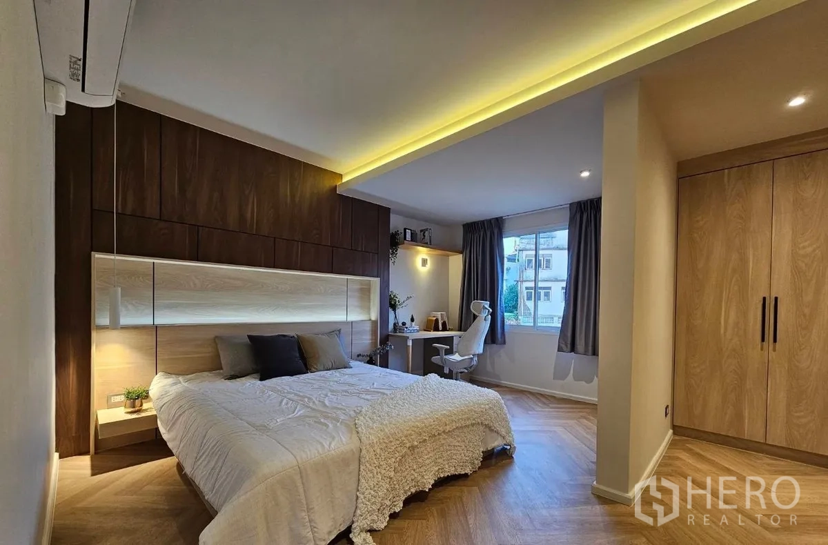 联排别墅 出租或出售在Watthana, Bangkok - 宽敞主卧，木质背景墙、衣柜与书桌。