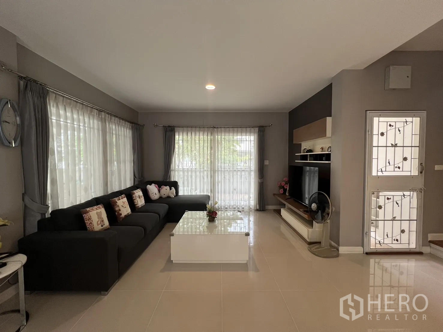 Detached House for rent in Bang Kapi, Bangkok - Bright living room with an L-shaped sofa, TV wall and glossy coffee table.