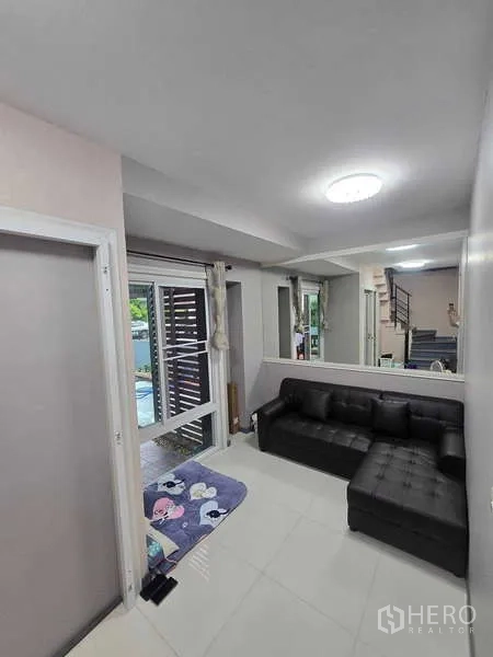 บ้าน ให้เช่าในLat Krabang, Bangkok - ห้องนั่งเล่นขนาดเล็ก โซฟาหนังสีดำ หน้าต่างบานใหญ่ และทางขึ้นบันได