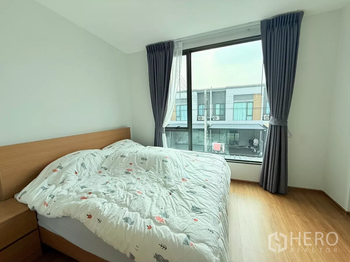 Townhouse for rent in Bang Phli, Samut Prakan - Master bedroom with large window, curtains, and wood-look flooring.