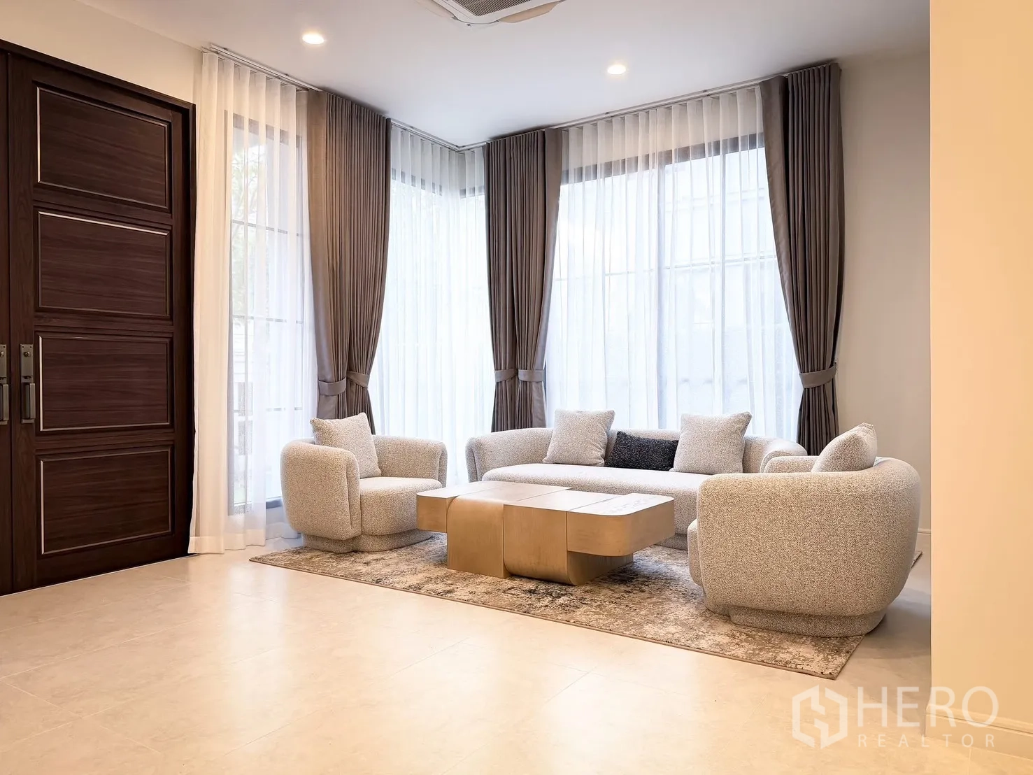 บ้านเดี่ยว for rent in Bang Khen, Bangkok - ห้องนั่งเล่นสว่าง โปร่ง ผ้าม่านกรองแสงเต็มผนัง ชุดโซฟาและประตูไม้บานใหญ่.