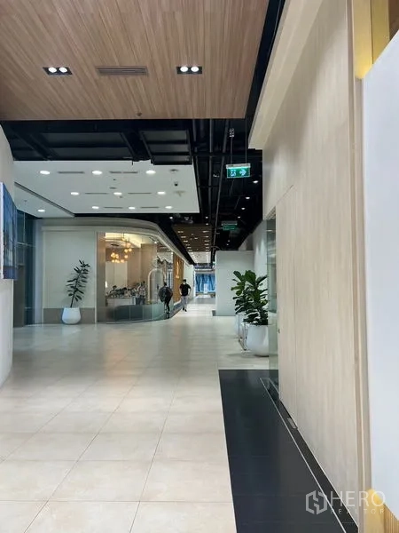 零售空间 出租 - Rama 9室内商业走廊，浅色地砖与木质天花，摆放绿植