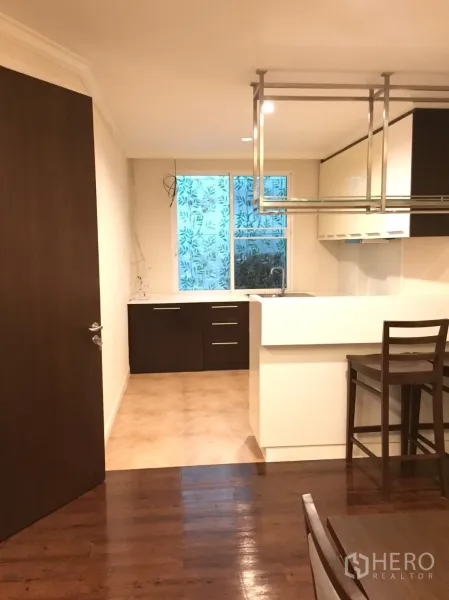 คอนโด ขายในHuai Khwang, Bangkok - ครัวสไตล์โมเดิร์นพร้อมเคาน์เตอร์บาร์ ที่แขวนโลหะ ตู้ไม้สีเข้ม และหน้าต่างบานใหญ่