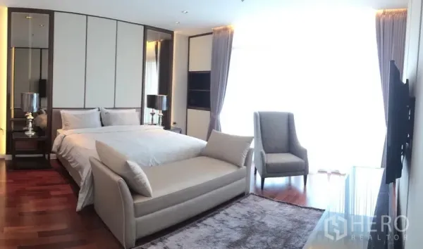 Condominium for rent in Pathum Wan, Bangkok - Spacious master bedroom with king bed, bench seat, hardwood floors and full-height curtains.