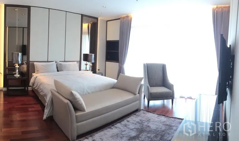 Condominium for rent in Pathum Wan, Bangkok - Spacious master bedroom with king bed, bench seat, hardwood floors and full-height curtains.