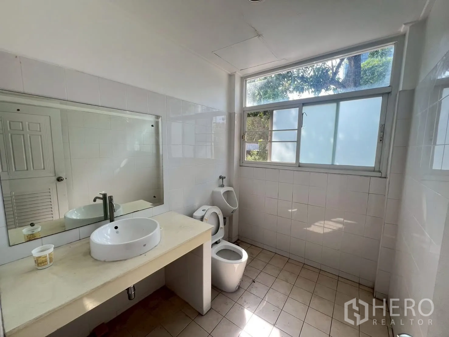 Detached House for rent in Watthana, Bangkok - Bright bathroom with a long vanity, toilet, urinal, and frosted window.
