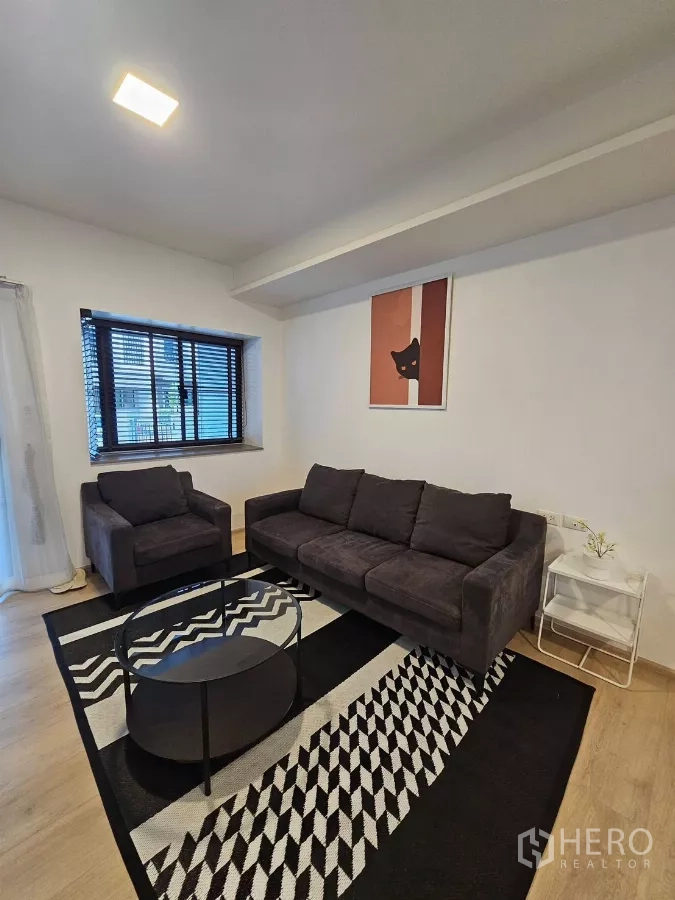 Townhouse for rent in Bang Phli, Samut Prakan - Cozy lounge with sofa, armchair and patterned rug beside window with blinds