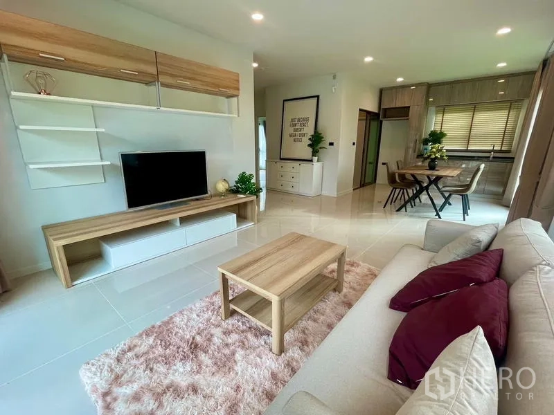 Detached House for rent in Bang Kapi, Bangkok - Living room with TV cabinet and shelving connected to dining space.