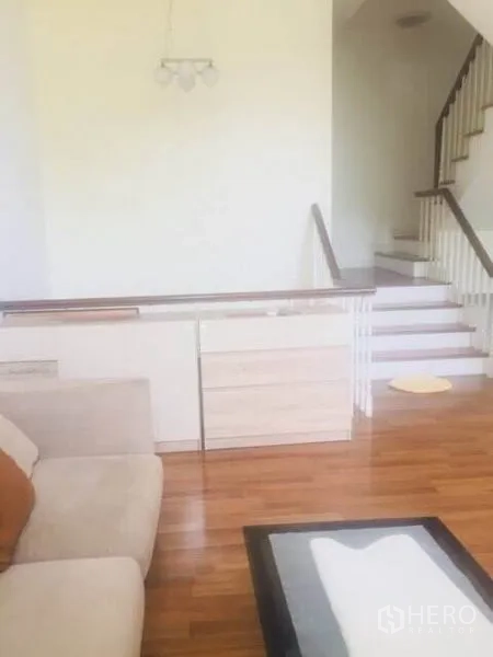 ทาวน์เฮาส์ ให้เช่าในBang Kapi, Bangkok - พื้นที่นั่งเล่นเปิดโล่ง พื้นไม้ และบันไดราวสีขาว