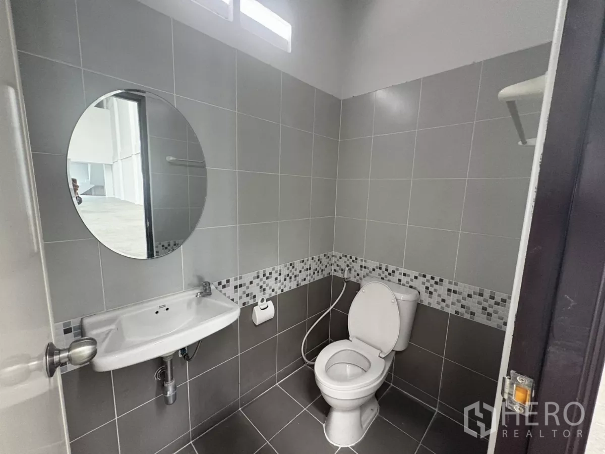 Factory for rent in Phra Samut Chedi, Samut Prakan - Ground-floor restroom with toilet, sink and gray ceramic tiles.