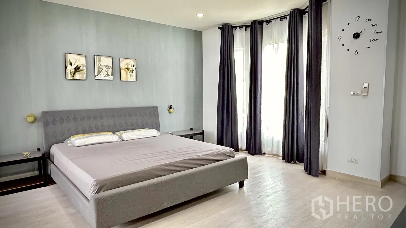 Townhouse for rent in Bang Kapi, Bangkok - Close-up of king-size bed beside large corner windows with dark curtains and sheer drapes.