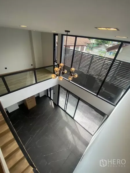 联排别墅 出租在Huai Khwang, Bangkok - 挑高客厅，黑色大理石地面、整面落地窗与现代吊灯。