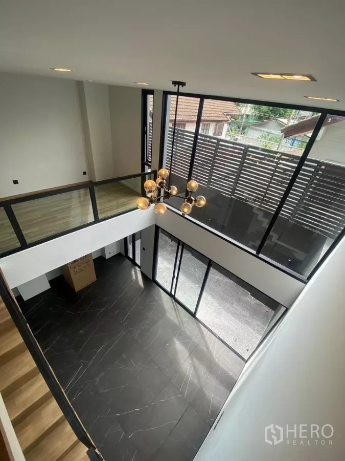 ทาวน์เฮาส์ ให้เช่าในHuai Khwang, Bangkok - ห้องนั่งเล่นเพดานสูง พื้นกระเบื้องหินอ่อนสีดำ ผนังกระจกเต็มบานและโคมไฟโมเดิร์น.