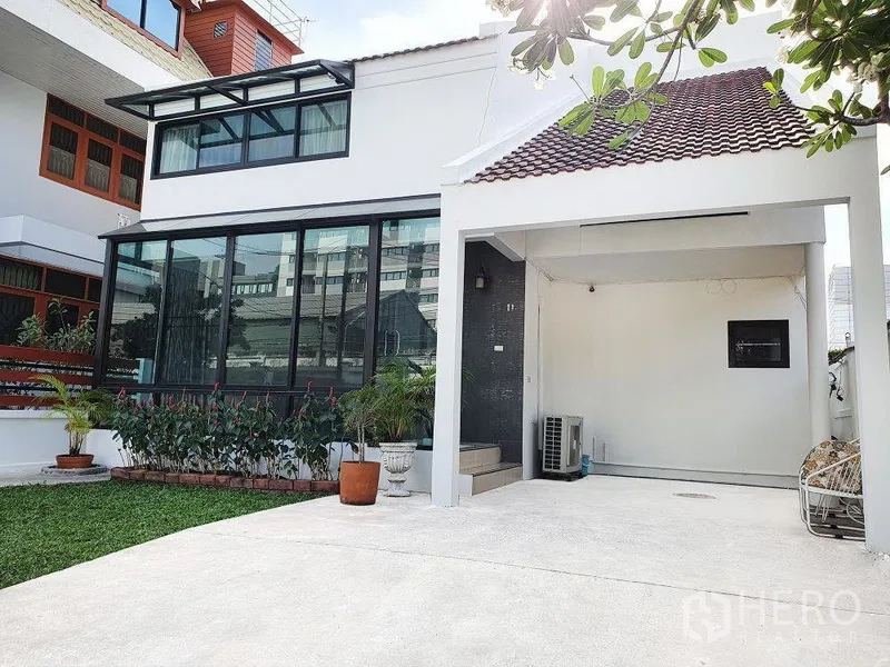 บ้าน ให้เช่าในPhra Khanong, Bangkok - ภายนอกบ้านเดี่ยวสองชั้น มีห้องกระจกขนาดใหญ่ โรงจอดรถ และสนามหญ้าตกแต่ง