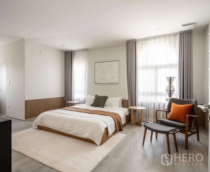 Detached House for rent or sale in Bang Phli, Samut Prakan - Spacious master bedroom with large windows, bed and accent armchair.