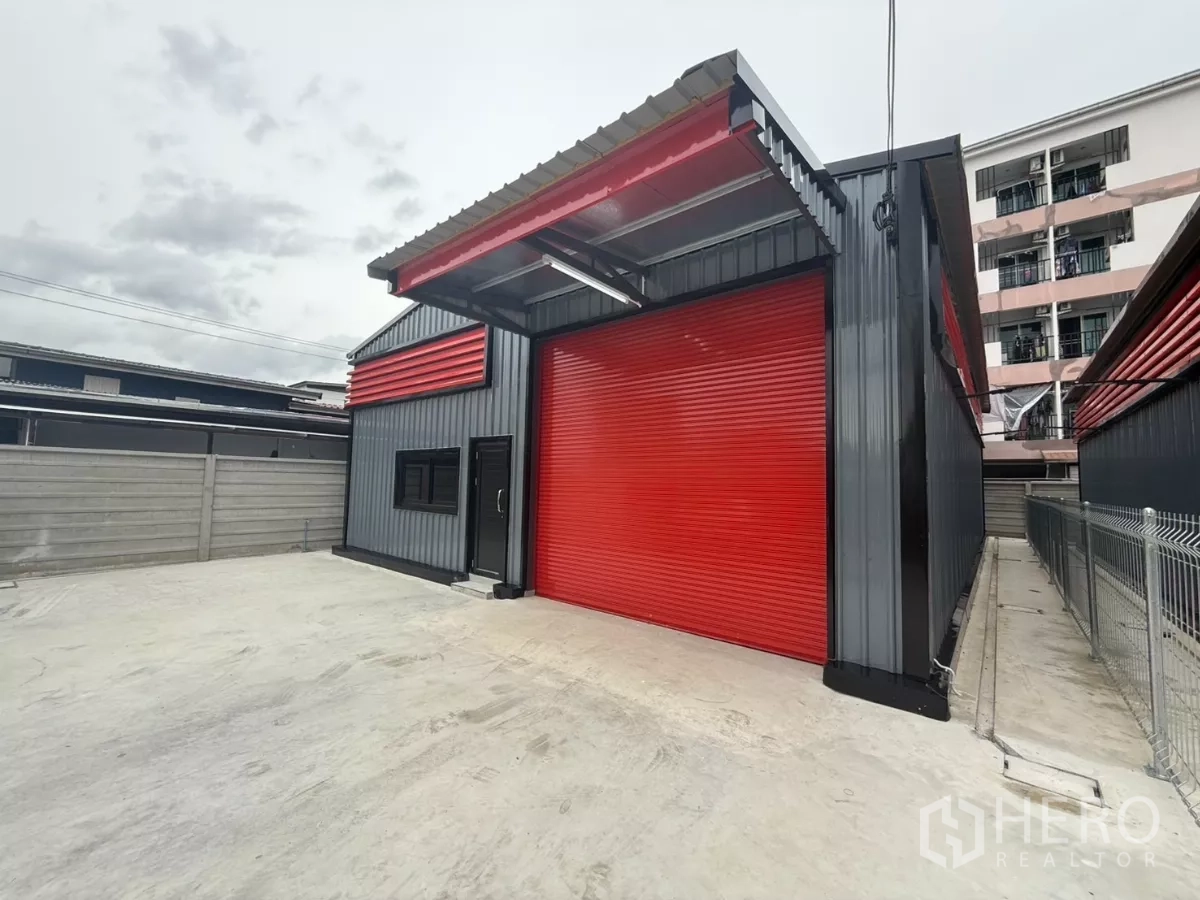 货栈 出租在Lat Phrao, Bangkok - 曼谷拉抛区仓库外观，红色卷帘门与宽敞混凝土装卸院。