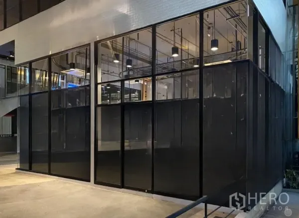 Retail Space for rent - Night view of a modern glass-fronted retail space with high ceiling and pendant lighting.