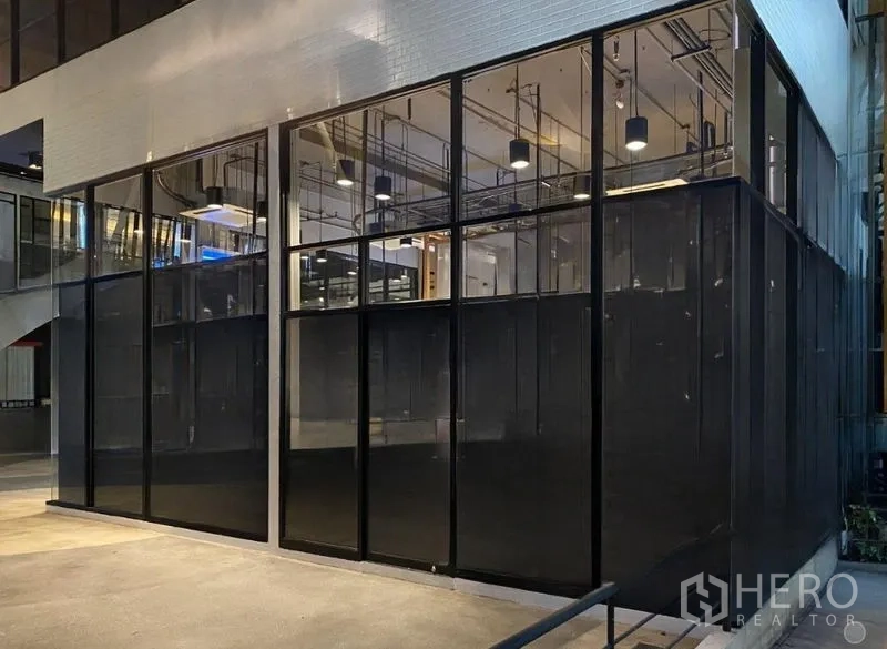 Retail Space for rent - Night view of a modern glass-fronted retail space with high ceiling and pendant lighting.