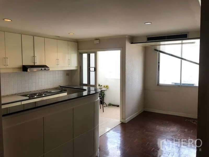 คอนโด ขายในWatthana, Bangkok - พื้นที่นั่งเล่นแบบเปิดพร้อมครัวตู้สีขาว เคาน์เตอร์บาร์ และประตูออกระเบียงเล็ก