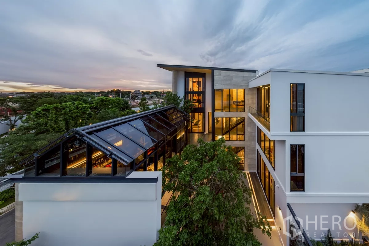 Detached House for rent in Saphan Sung, Bangkok - Aerial angle of the villa showing glass-roof conservatory linking wings and expansive windows among mature trees.