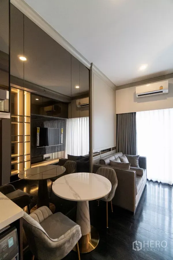 公寓 出租在Watthana, Bangkok - 通罗区公寓客厅，配沙发、电视墙、圆形餐桌与落地窗帘。